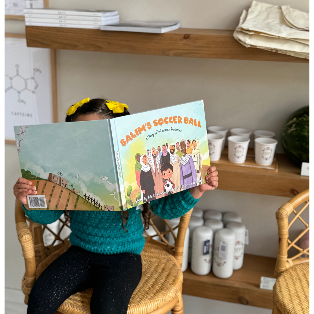 Young girl reads Salim’s Soccer Ball: A Story of Palestinian Resilience while seated in a cozy bookstore setting.